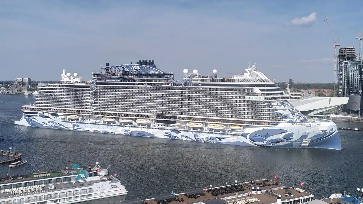 Norwegian Prima de NCL navegando al atardecer con la cubierta panorámica iluminada